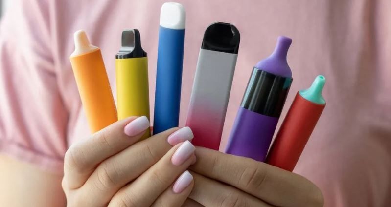 a hand holding a bunch of colour vapes