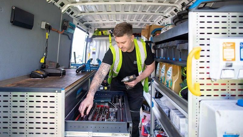 A man holding tools in the back of a van 