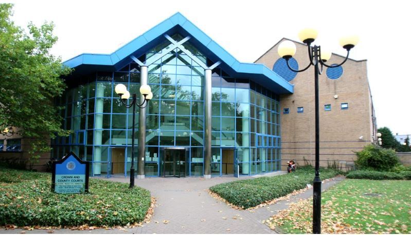 The outside of Basildon Crown Court, a glass-fronted building with green space and path leading up to its front door