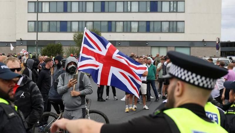 Protestors hold a GB-flag outside the Holiday Inn Express