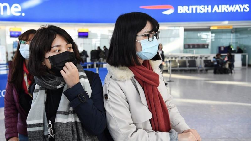 People arrive at Heathrow Airport wearing face masks