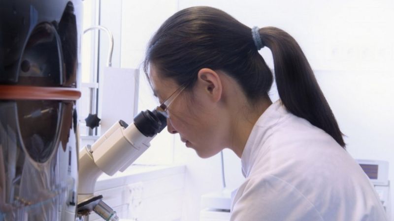 A woman in a white lab coat deep in thought, symbolizing the intellectual rigor women brought to anthropology