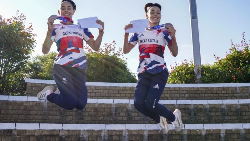 Jessica and Jennifer Gadirova jumping while holding their medals and exam results