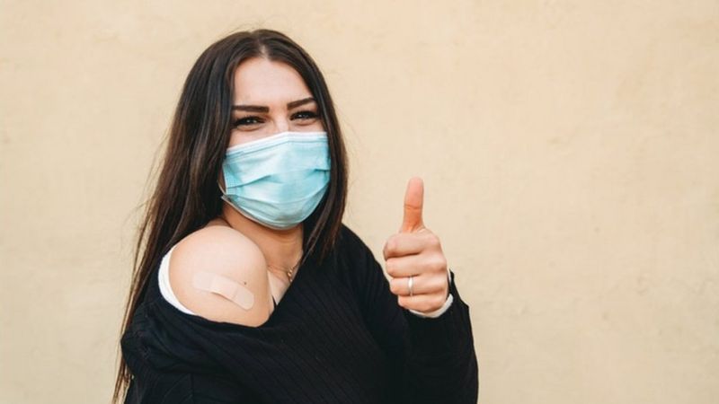 Mujer sonriendo con la mascarilla después de recibir la vacuna