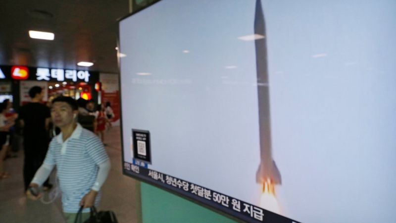 Un hombre pasa por una pantalla que muestra un misil