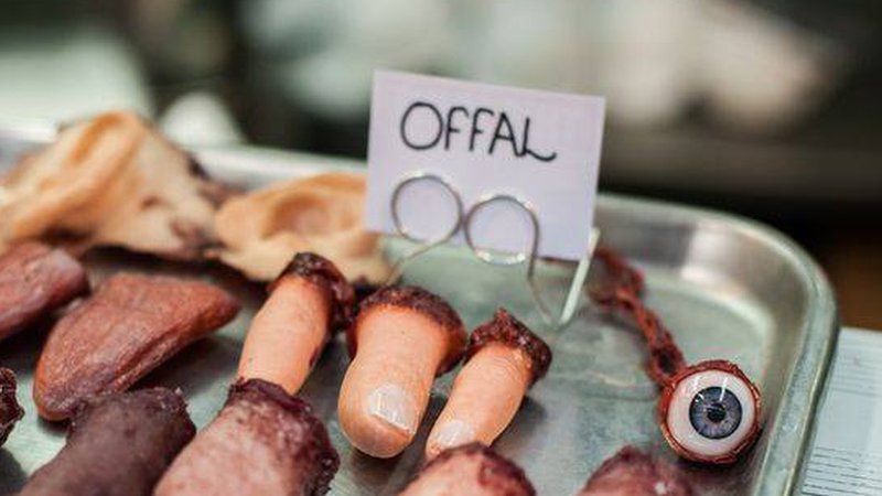 Tray with eyeball, mocked up human fingers, sign saying Offal