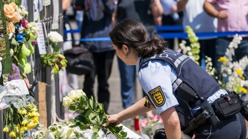 A police woman lays flowers at the memorial for a police officer in Mannheim
