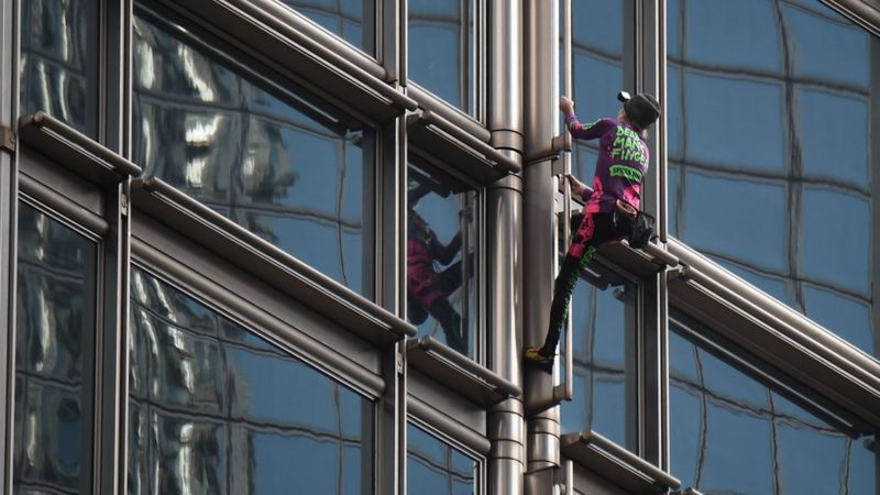 Seorang pendaki asal Perancis yang dikenal dengan sebutan 'Spiderman' memanjat gedung pencakar langit di Hong Kong dan memasang spanduk besar, Jumat (16/8/2019).