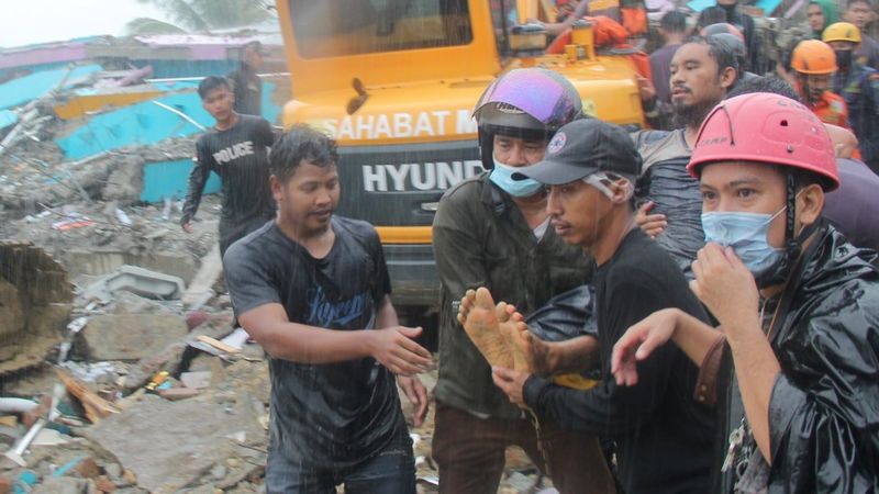Petugas mengevakuasi korban yang terjepit dari bangunan di rumah sakit Mitra Manakarra yang runtuh akibat gempa bumi di Mamuju, Sulawesi Barat, Jumat (15/1/2021).
