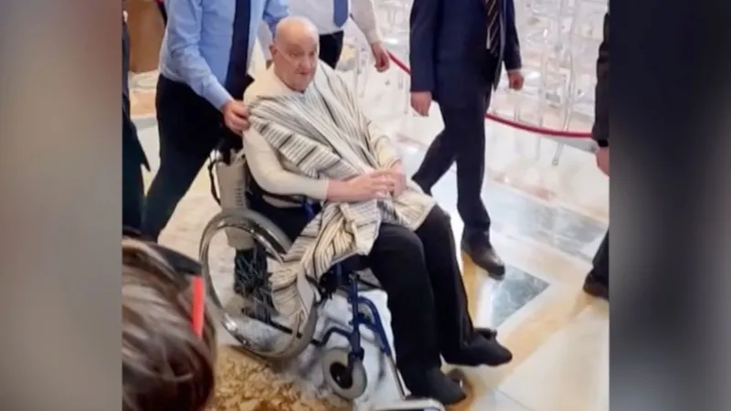 Screengrab of Pope in wheelchair, wearing black trousers, a white shirt and a scarf