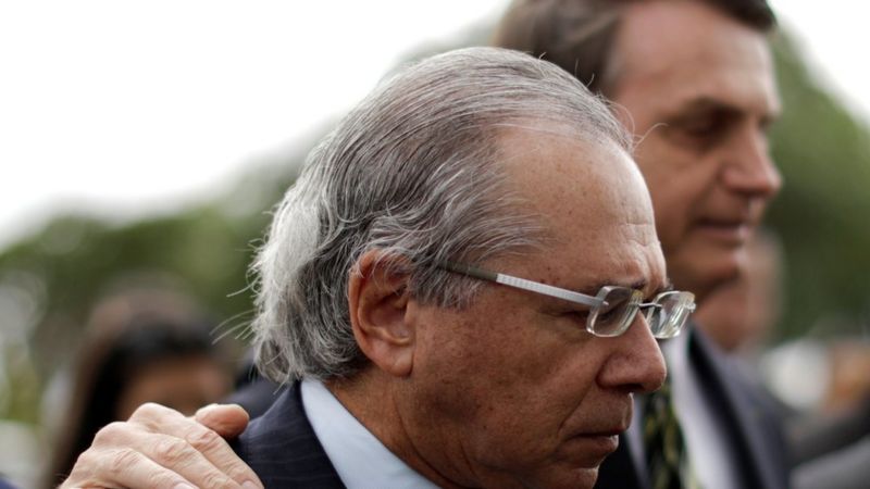 Paulo Guedes e Jair Bolsonaro aparecem abraçados e de perfil