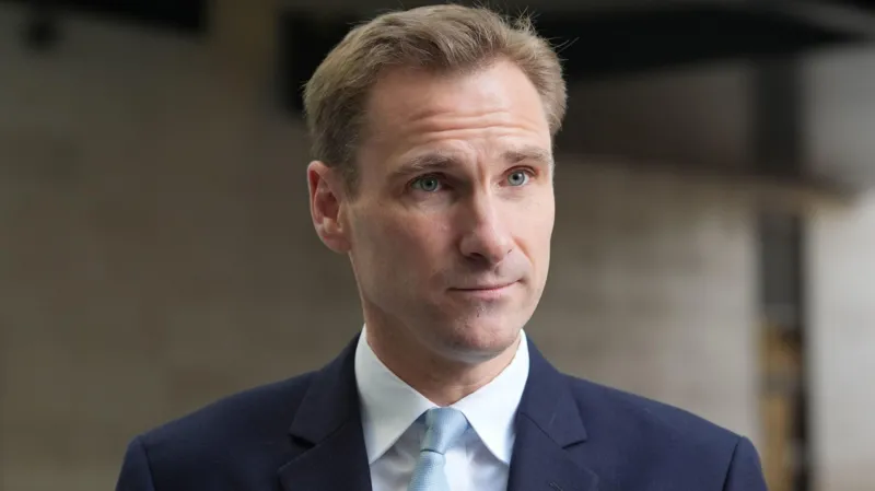 Shadow home secretary Chris Philp wears a blue suit and tie.