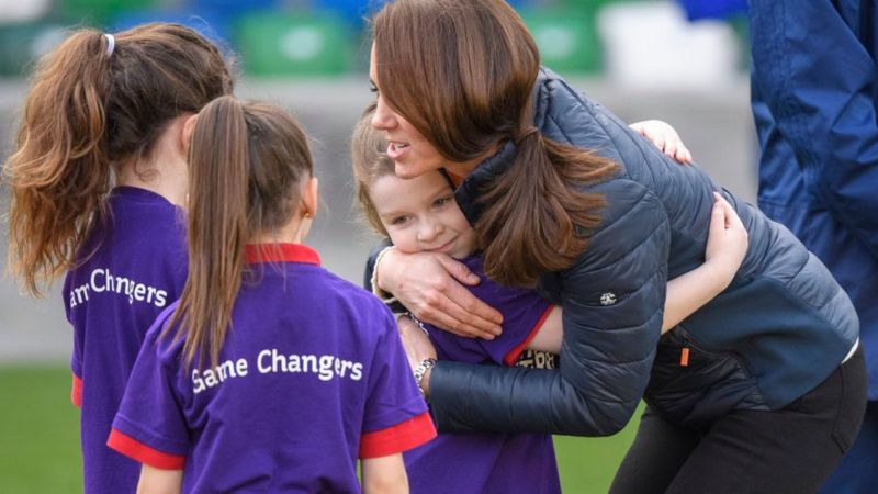 Duchess of Cambridge hugs a girl.