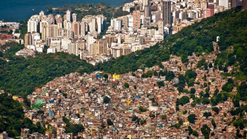Imagem aérea do Rio de Janeiro que mostra a favela da Rocinha à frente e prédios mais ricos ao fundo