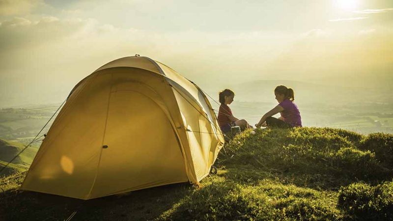 Two people sitting by a tent