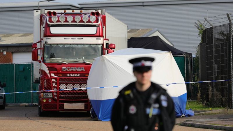 A police officer stands watch in front of the lorry