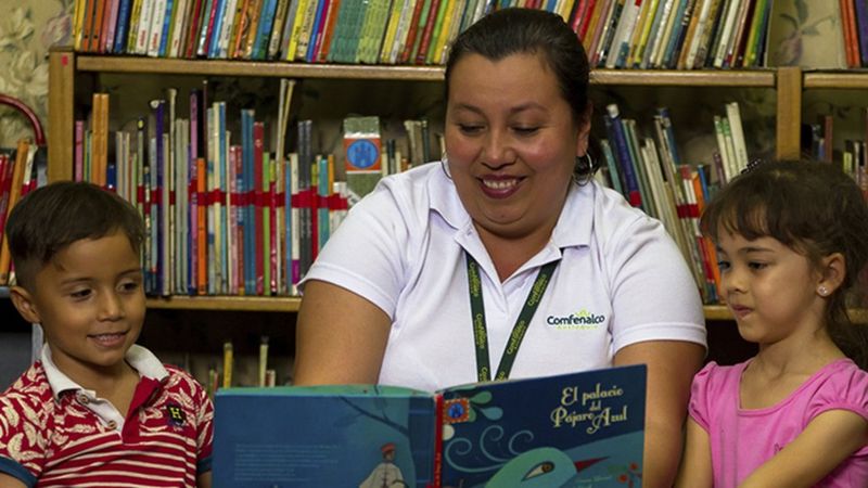 Una mujer lee un libro a unos niños en Medellín