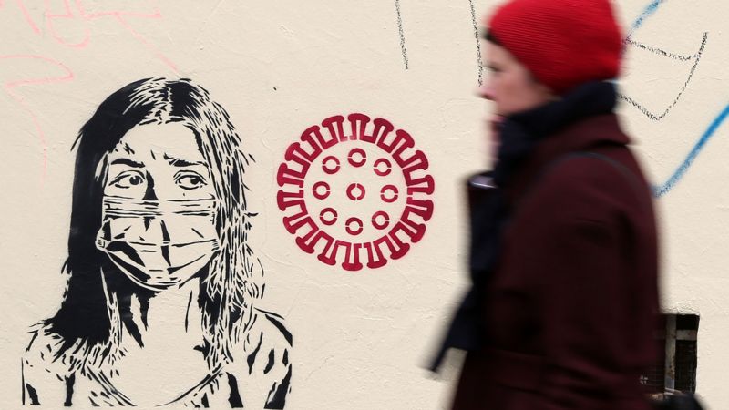 Women walks past graffiti. March 30, 2020, Berlin, Germany