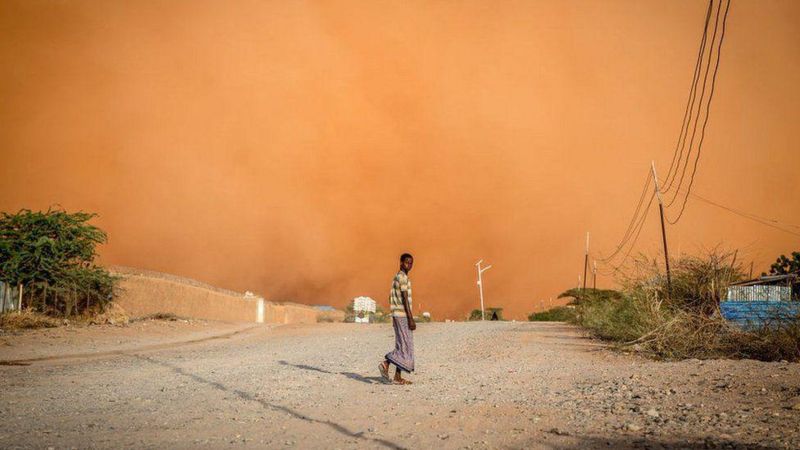 Jovem caminhando em meio a tempestade de areia na Somália