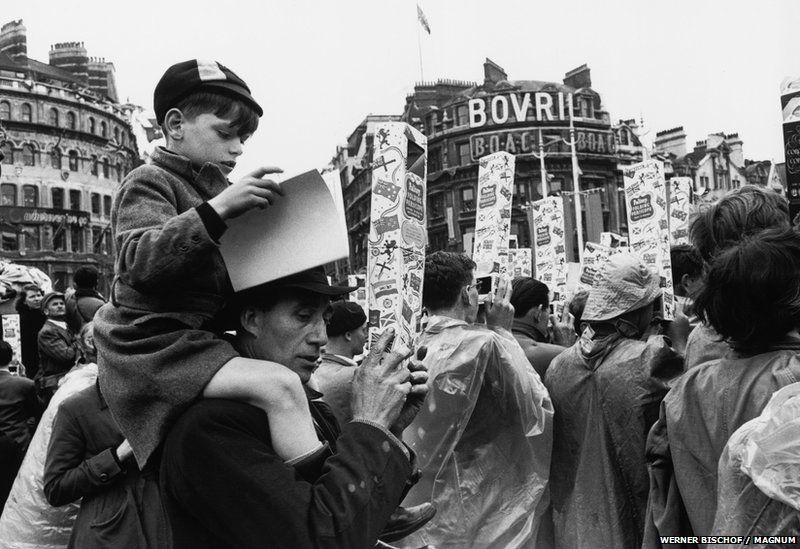 A young boy on his father's shoulders amongst the crowd