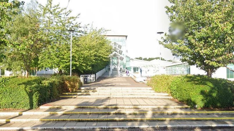 A Google Maps image of steps and trees leading up to the large glass façade of Spectrum Leisure Centre in Guildford with 