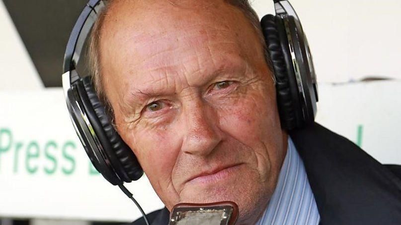 Edwin Overland wearing headphones and talking into a lip mic at a sports ground