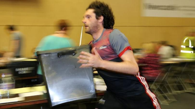A young man runs carrying a large grey box