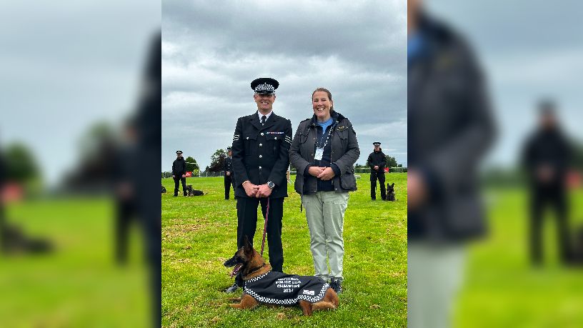 Sergeant Nick Dalrymple stands with a judge at the police dog trials, with Eva lying down