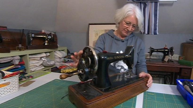 Nikki Field spinning the wheel of a black Singer sewing machine