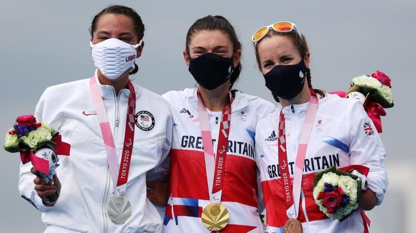 (Left to right) Grace Norman, Lauren Steadman and Claire Cashmore connected nan podium pinch their medals, while wearing masks, astatine nan Tokyo 2020 Paralympics