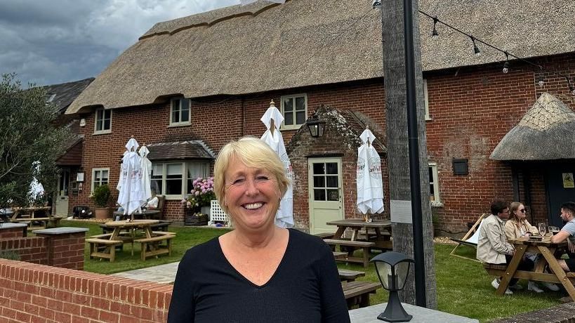 Deborah Risbridger standing in front of The Elm Tree pub