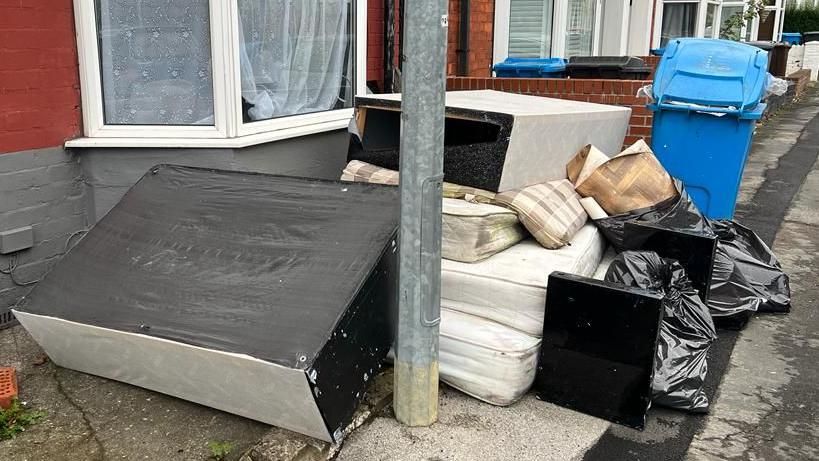 Divans, mattresses and rubbish piled up in a garden