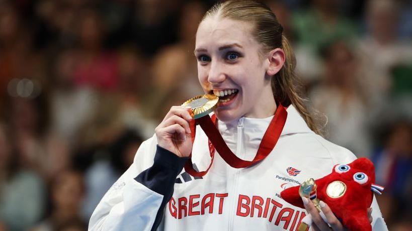 Louise Fiddes bites her gold medal