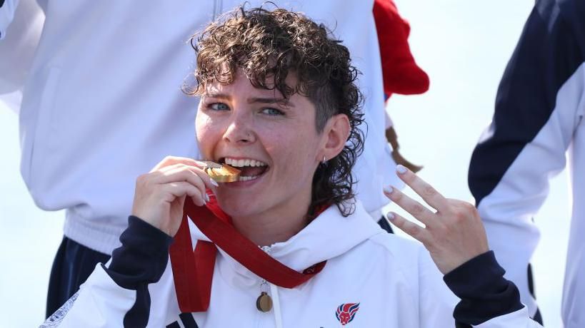 Lauren Rowles holding the Paralympic gold medal for winning the PR2 mixed double sculls