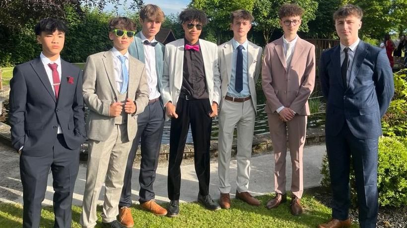 Boys dressed up in suits and ties looking at the camera at their prom