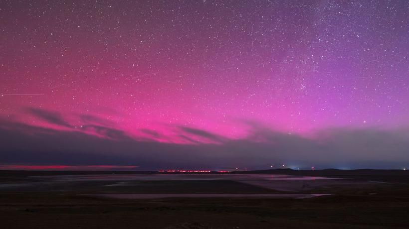 Stars shine against a bright pink and purple night sky