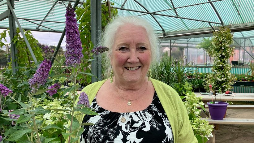 A smiling woman stood next to plants