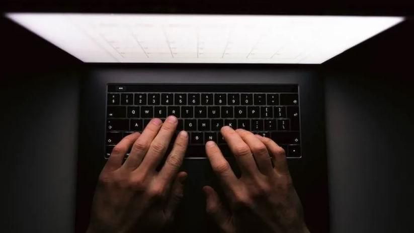 A overview shot of a pair of hands tapping on a black laptop