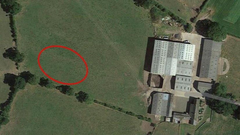 Birds eye view of a farm in Dalston. A superimposed red circle on a field to the left indicates the proposed site of the slurry lagoon. To the right, a farm building is seen from above.
