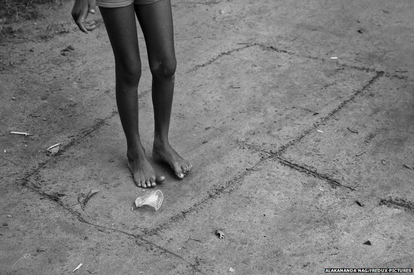 A girl plays hopscotch with a battered plastic glass in a Bangladesh enclave in India.