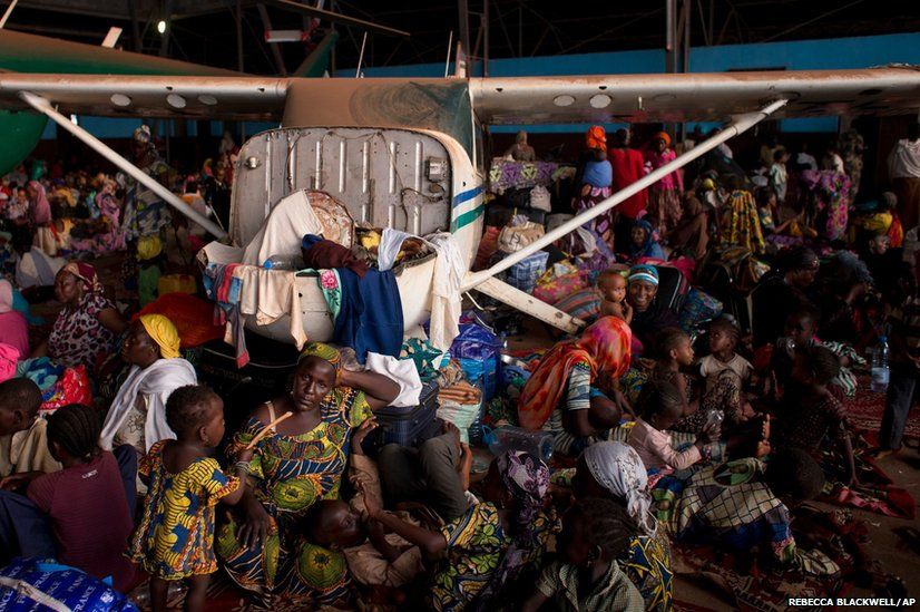 Chadians waiting for evacuation flights settle in for the night inside an airport hangar in Bangui, Central African Republic
