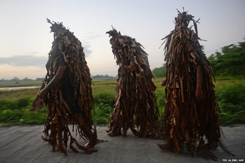 Residents covered in mud and wearing costumes made from banana leaves take part in the Catholic feast day of Saint John the Baptist in Aliaga, Philippines
