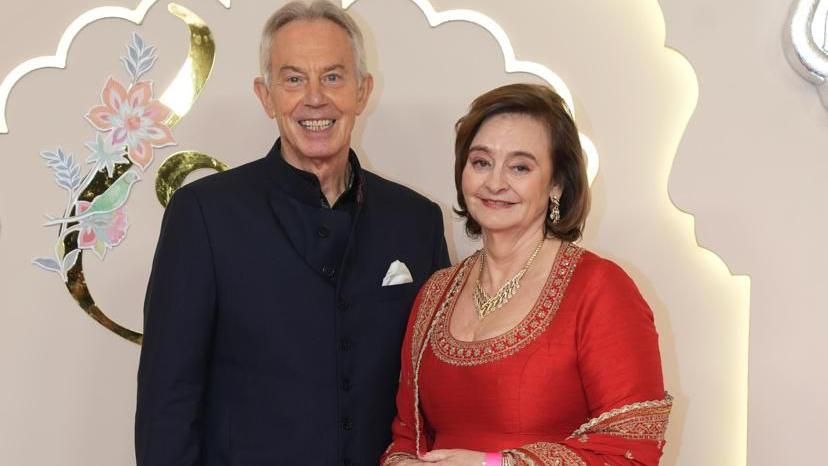 Tony Blair and his wife Cherie smile at the camera.