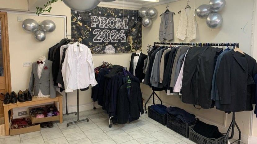 Suits and shirts are hung up in the Prom Dreams shop with a Prom 2024 banner in the background