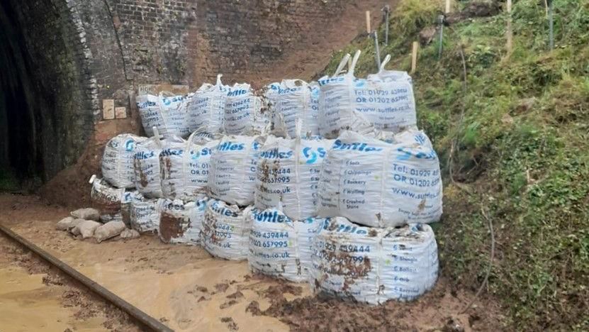 Picture of the landslip at the entrance to the Honiton Tunnel. Sandbags are visible.