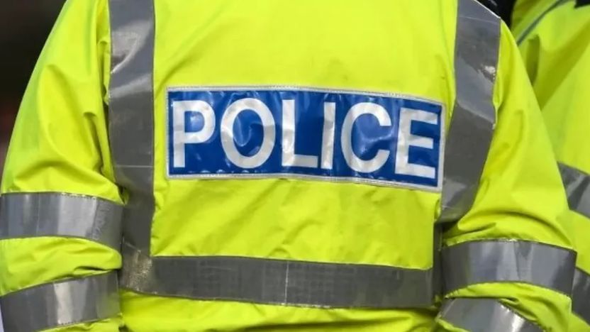 the back of a police officer uniform. It is yellow with the words 'Police' inscribed. 