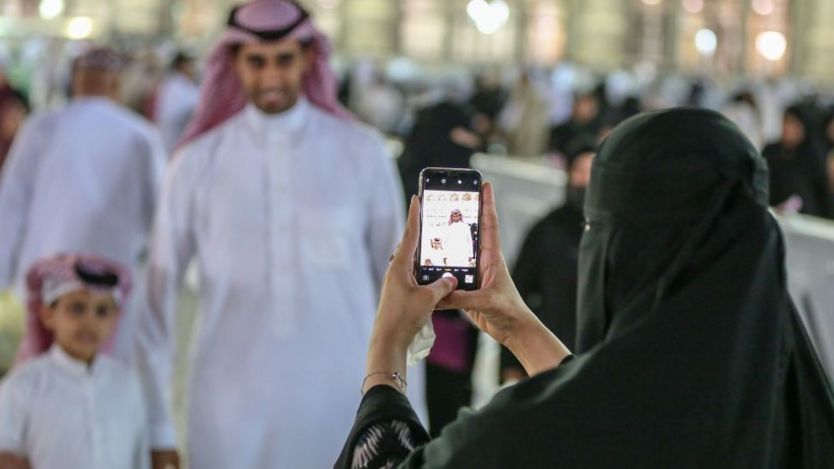 Seorang perempuan mengambil foto keluarganya di Masjid al-Haram, Mekah.