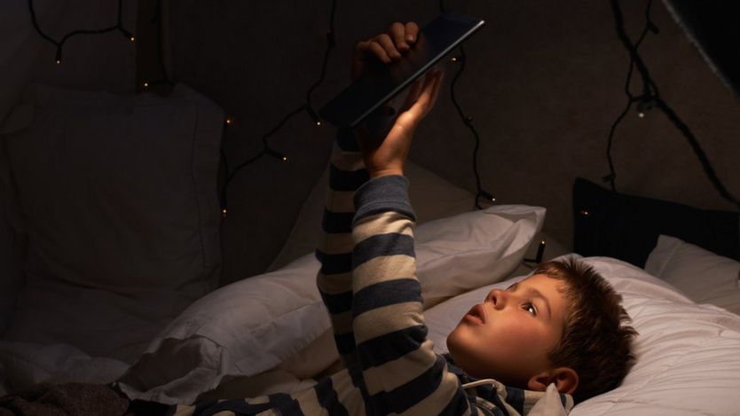 Boy looking at tablet on bed