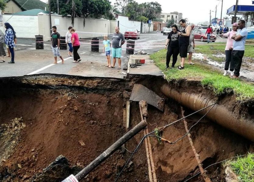 People stand on a damaged road after massive flooding in Amanzimtoti, near Durban, South Africa April 23, 2019