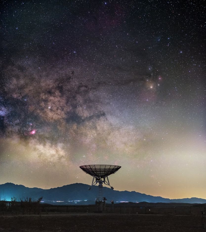 The Milky Way rises ominously above a small radio telescope